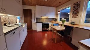 a large kitchen with white cabinets and a wooden floor at Villa with great view in Sandnes +9 photos