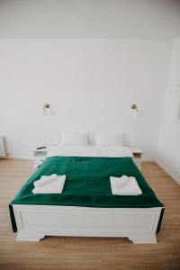 a white bed with green sheets and pillows on it at Studio Manzur in Braşov