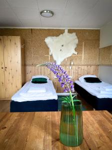 Cette chambre comprend 2 lits et un vase avec des fleurs sur une table. dans l'établissement Lumi Guest House, à Arvidsjaur