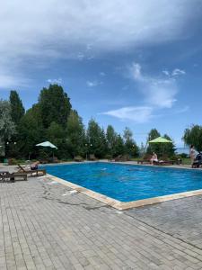 a large blue swimming pool with benches and umbrellas at Апартаменты Карвен Иссык-Куль Karven Issyk-Kul in Bulan Sogottuu