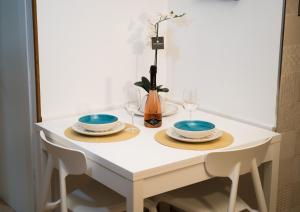 a white table with two plates and wine glasses at Meraki House in Alghero