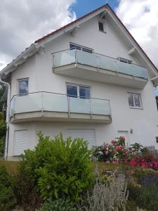 ein weißes Haus mit einem Balkon und einigen Blumen in der Unterkunft Ferienwohnung An der Karlskuppe in Eisenach