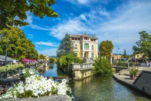 a building next to a river in a city at Le Nid'Isle - Stationnement privé gratuit - Wi-Fi performant - Climatisation in LʼIsle-sur-la-Sorgue