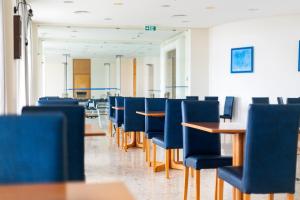 uma sala de jantar com cadeiras e mesas azuis em Hotel do Mar em Povoação