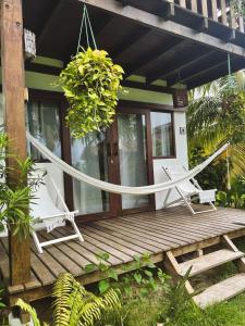 伊卡萊的住宿－Pousada Pais Tropical，木屋配有2把椅子和木制甲板上的吊床