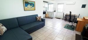 a living room with a blue couch and a kitchen at Maris full apartment with roof garden access in Chios