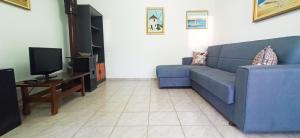 uma sala de estar com um sofá azul e uma televisão em Maris full apartment with roof garden access em Quios