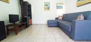 a living room with a blue couch and a tv at Maris full apartment with roof garden access in Chios