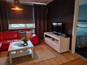 een woonkamer met een rode bank en een tv bij Apartament Wyszyńskiego Szczecin Polska in Szczecin
