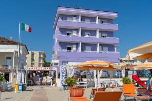 ein lila Gebäude mit orangefarbenen Stühlen und Sonnenschirmen in der Unterkunft Beach Suite Hotel in Bellaria-Igea Marina