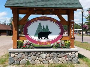um sinal para um museu de ursos pardos com um urso negro em Boulder Bear Motor Lodge em Boulder Junction