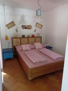Un dormitorio con una gran cama de madera con sábanas rosas. en Uj Vilag, en Harkány