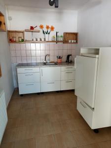 cocina con armarios blancos y nevera blanca en Uj Vilag, en Harkány