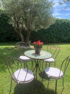 una mesa con 4 sillas y un jarrón con flores en Casa Rural LOS TINES en Bustarviejo
