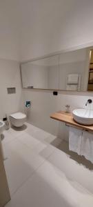 a white bathroom with two toilets and a sink at Casa Raiola Ercolano Luxury Rooms & Spa in Ercolano