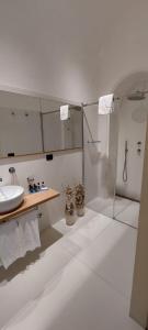 a white bathroom with a sink and a shower at Casa Raiola Ercolano Luxury Rooms & Spa in Ercolano