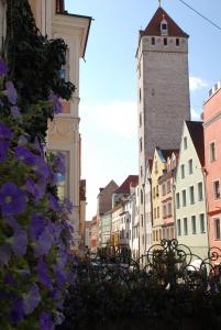 una calle de la ciudad con edificios y flores púrpuras en Hotel Orphée - Kleines Haus, en Regensburg