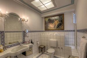 ein Badezimmer mit einem Waschbecken, einem WC und einem Gemälde in der Unterkunft Hotel Orphée - Kleines Haus in Regensburg