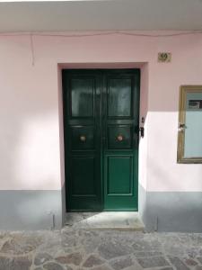 a green door in a white building with a wall at La Porta sul Mare in Pizzo