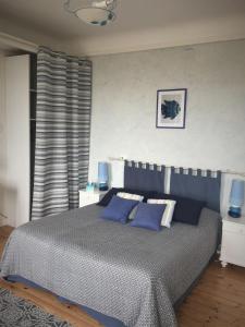 a bedroom with a large bed with blue pillows at Le Logis du Canal in Marennes
