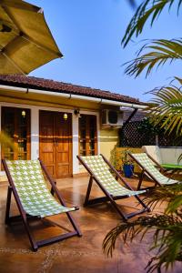 two lawn chairs sitting on a patio in front of a house at Serendipity House Goa in Nerul