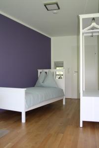 um quarto com uma cama branca e uma parede roxa em Felseck Zimmer em Innsbruck