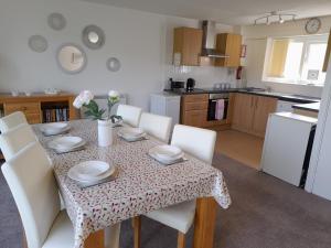 mesa de comedor con sillas blancas y cocina en Cornwall Countryside Lodges "Reserve Worldwide" Honicombe en Gunnislake