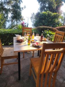 een houten tafel met eten en drinken erop bij Maddy's Kitchen and Accomodation in Gisenyi