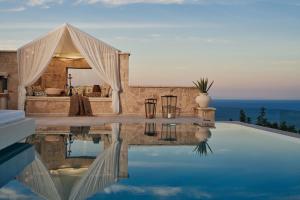 a villa with a swimming pool next to the ocean at Emerald Villas & Suites - The Finest Hotels Of The World in Agios Nikolaos