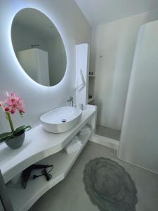Baño blanco con lavabo y espejo en All Blue Suites en Ambelas