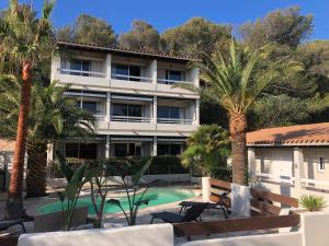 an apartment building with a swimming pool and palm trees at Hôtel de la plage in Agay - Saint Raphael