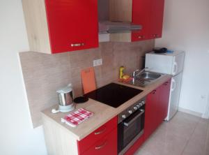 a small kitchen with red cabinets and a sink at Dragica 2 in Palit