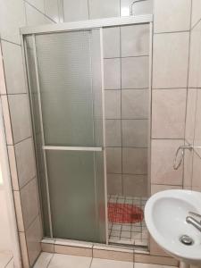 een douche met een glazen deur naast een wastafel bij Sunrise Lodge in Kaapstad