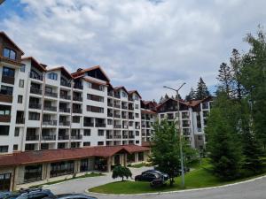 a large apartment building with cars parked in a parking lot at Mountain Paradise in Aparthotel Borovets Gardens in Borovets