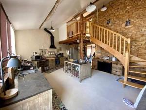 a large kitchen with a wooden staircase in a room at La grange in Promilhanes