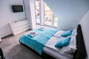 a bedroom with a bed with blue pillows and a window at Apart Bałtyk Pokoje & Apartamenty in Łeba