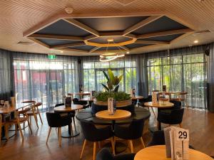 a restaurant with tables and chairs and large windows at Meadowbrook Hotel Brisbane in Loganlea