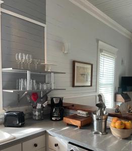 a kitchen with a counter with glasses on the wall at 150 year old Restored Lincolnville cottage in Saint Augustine
