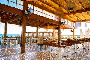 um restaurante com mesas e cadeiras e o oceano em Chamada Prestige Hotel and Casino em Cirénia