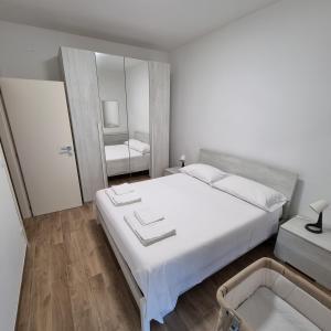a bedroom with a large white bed and a mirror at Appartamento Corallo in Porto Recanati