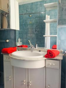 a bathroom with a white sink and red towels at La casina del Reloj con vistas al mar in Lastres