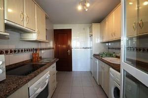 a large kitchen with white cabinets and a brown door at Balcones del Chaparral, Mijas Costa in Mijas Costa