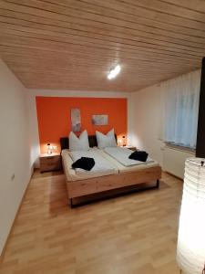 a bedroom with a large bed with an orange wall at Ferienwohnung Aichelberg in Aichelberg