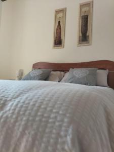 een slaapkamer met een wit bed met twee foto's aan de muur bij Apartment Dea in Cles