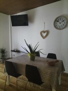 een eettafel met stoelen en een klok aan de muur bij Apartment Dea in Cles