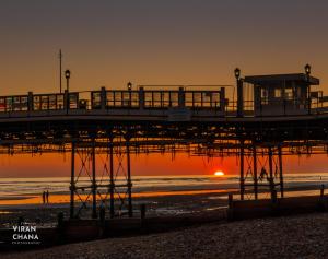 a pier at the beach with the sun setting in the background at The Studio in Worthing