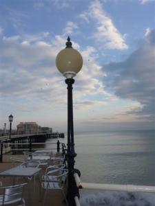 a street light next to a pier with tables and chairs at The Studio in Worthing