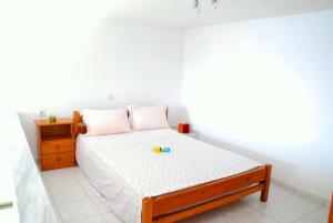 a white bedroom with a bed with a wooden frame at Studios Efi in Kala Nera