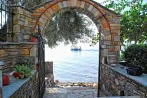 an archway in a stone wall next to the water at Studios Efi in Kala Nera
