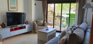 uma sala de estar com um sofá e uma televisão de ecrã plano em Apartamento con jardín y piscina em Marbella